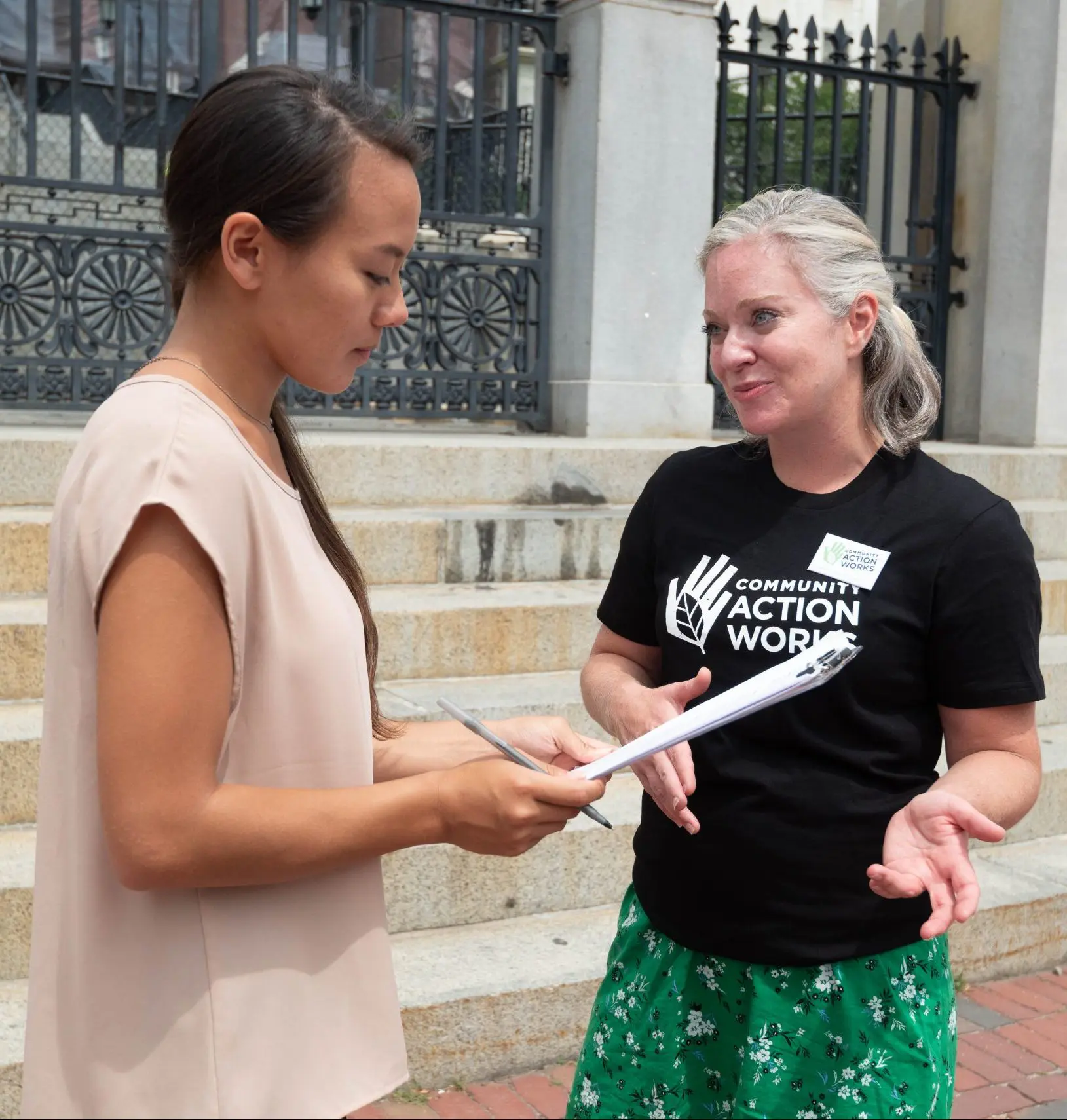 Two women engaged in a conversation on the steps of a modern building.